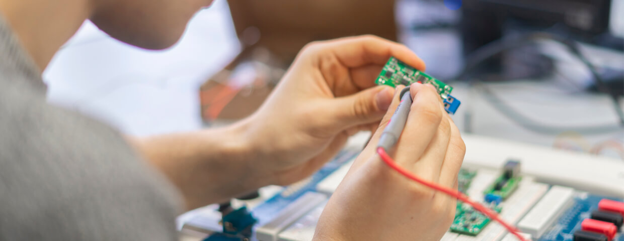 young man in special zoom magnifying glasses work with parylene electronic chip